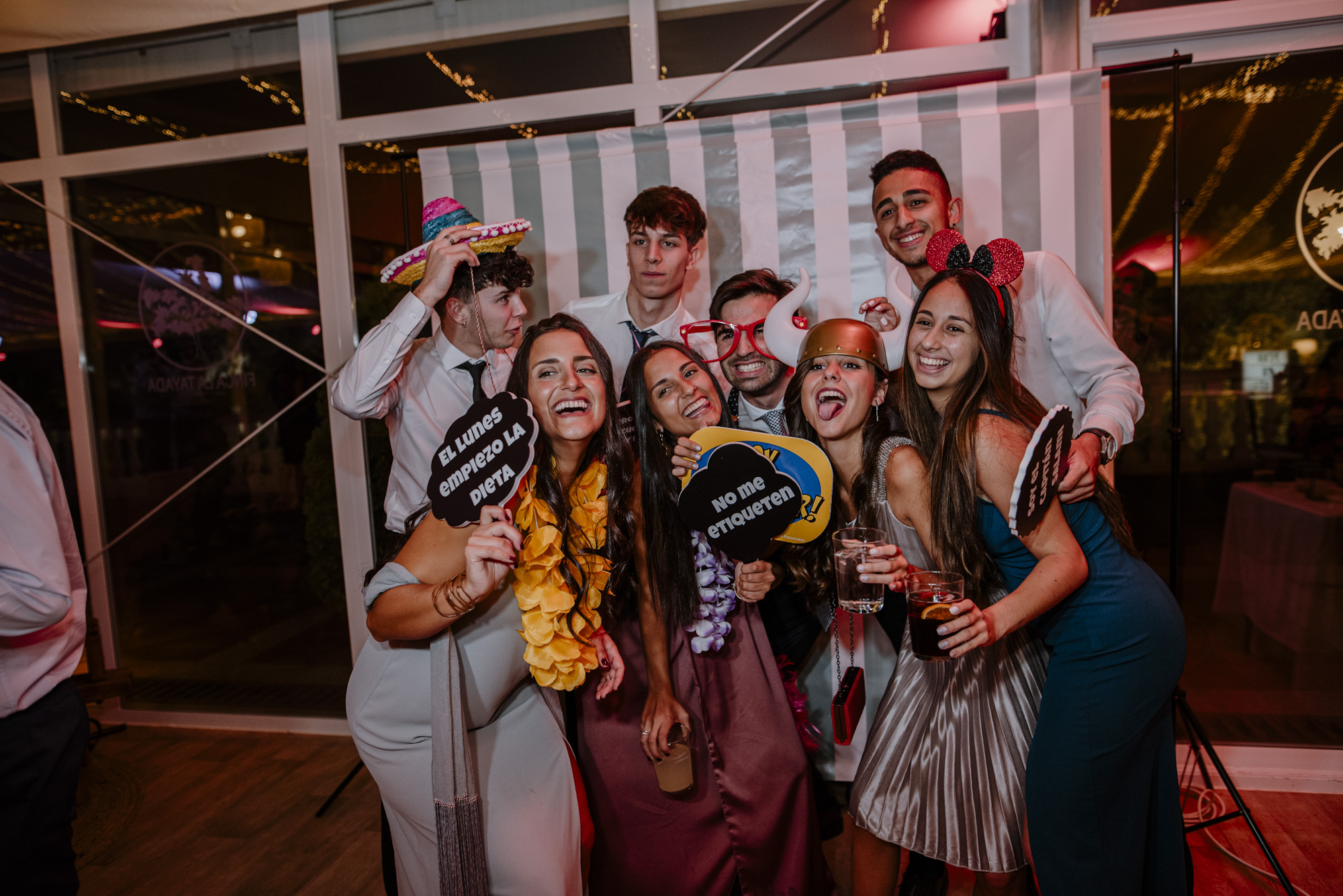 Invitados posando en el fotomatón de una boda con atrezzo y fondo profesional